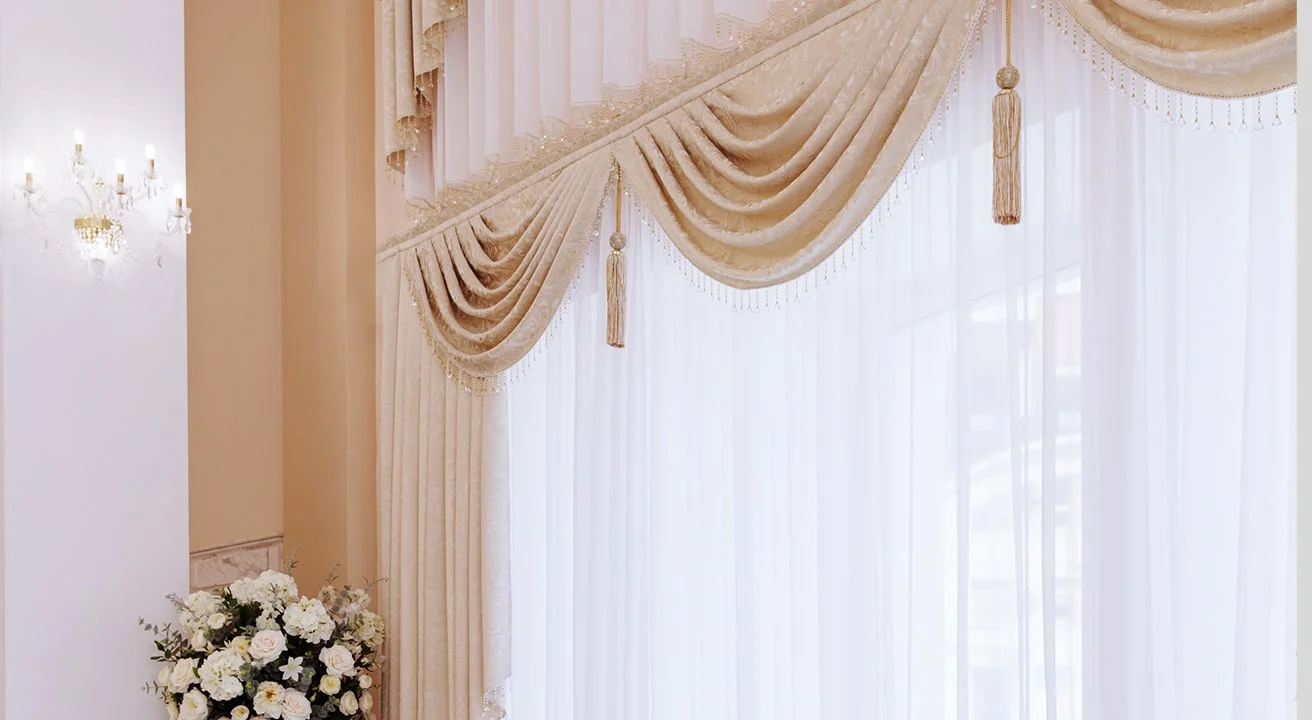 Elegant room with draped beige curtains and flowers.