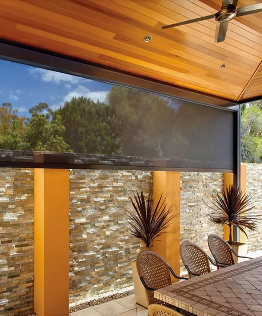 Outdoor patio with stone wall and ceiling fan.