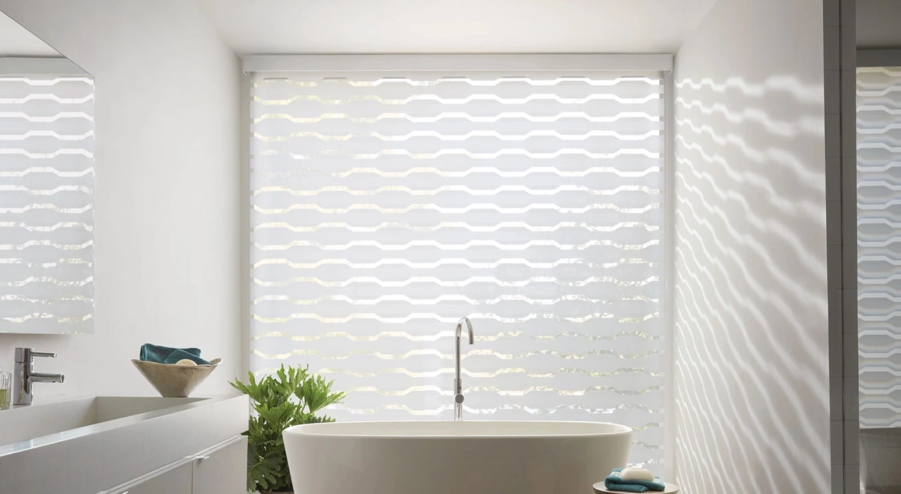 Modern bathroom with freestanding tub and patterned blinds.
