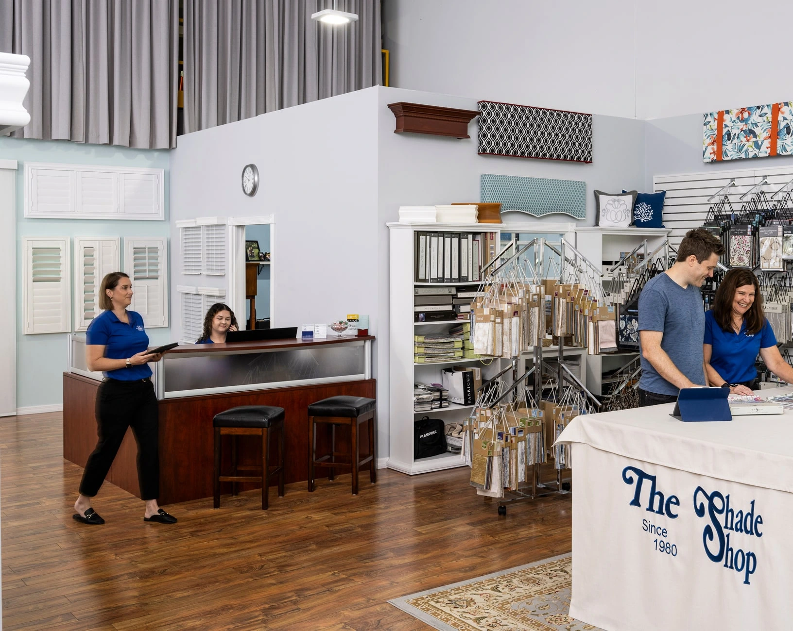 Employees assist customer in window treatment shop.