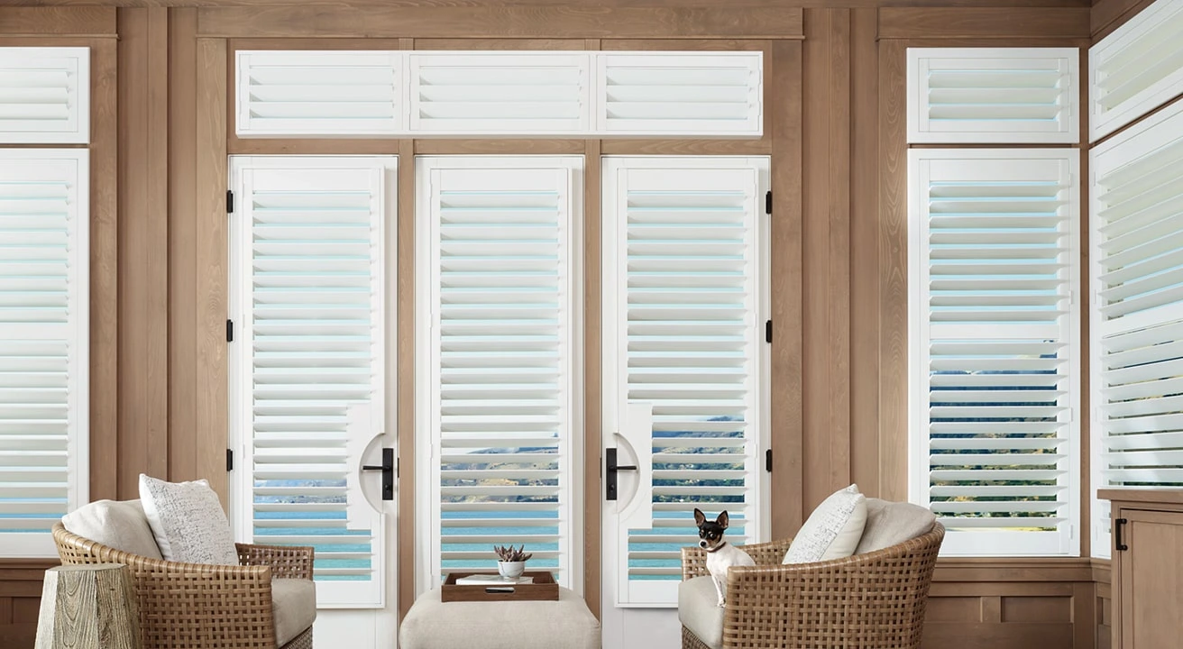 Living room with large white shutters and ocean view.