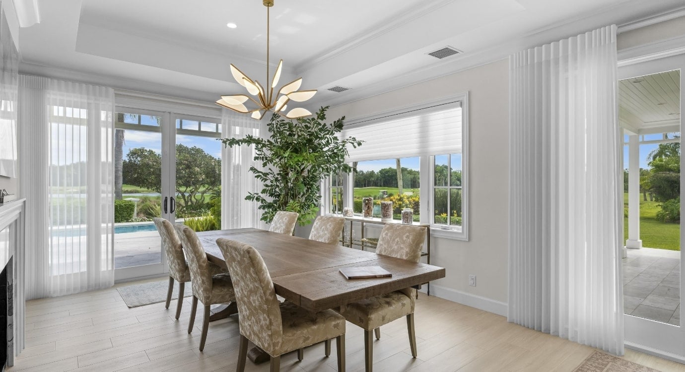 Elegant dining room with garden view and chandelier.