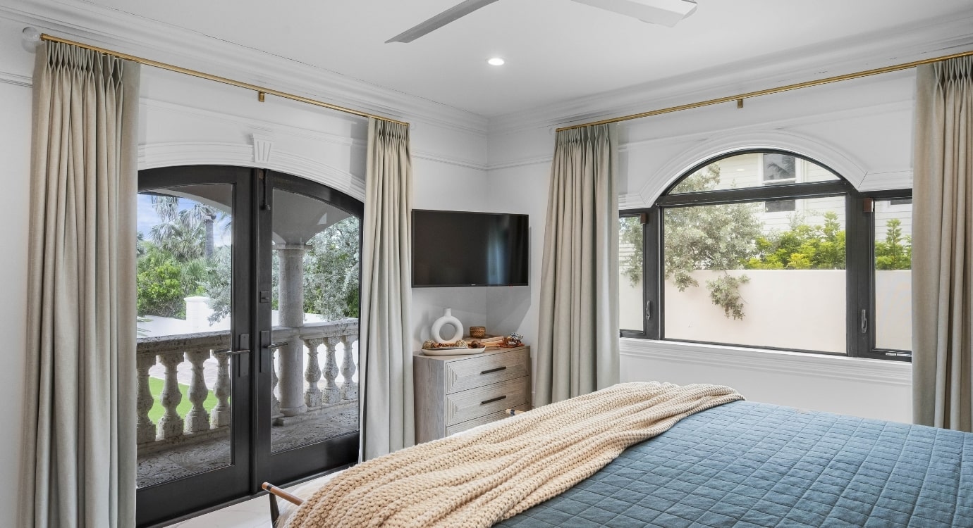 Modern bedroom with balcony view and open windows.